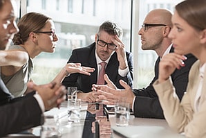 Team diskutiert hitzig am Tisch, Konfliktcoaching mit Führungskraft als Moderator