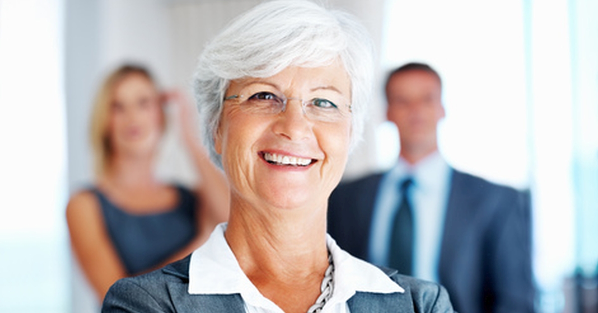 Selbstbewusste Frau im Business-Outfit mit zwei Gesprächspartnern in einer Verhandlung